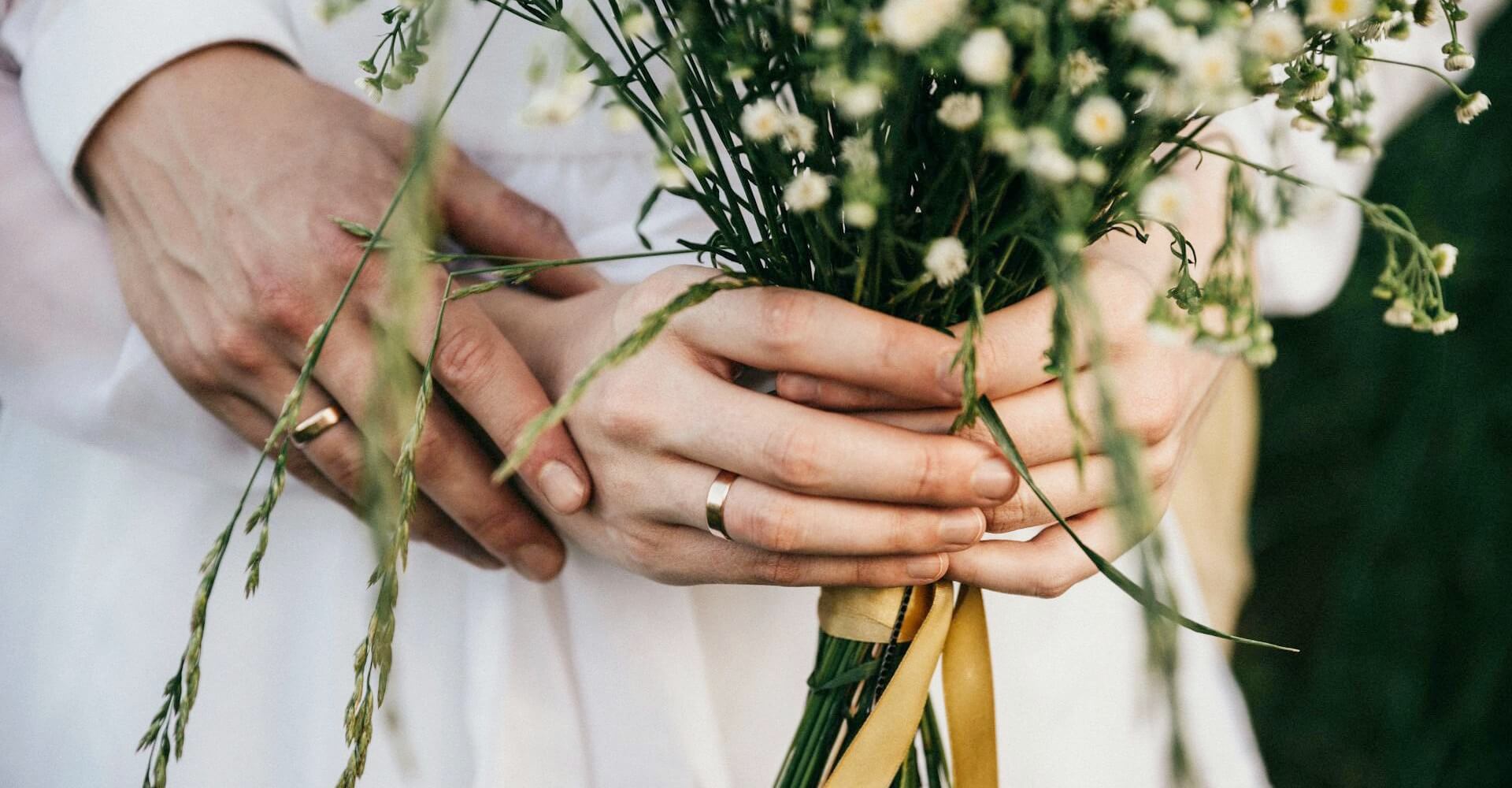花を一緒に持つ花嫁と花婿の手
